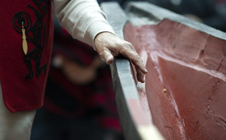 A picture of a craftperson's hand over a canoe being built